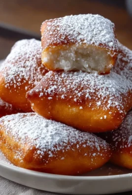 Fluffy vanilla beignets dusted with powdered sugar on a plate