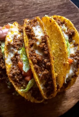 Crispy ground beef tacos on a plate with fresh toppings