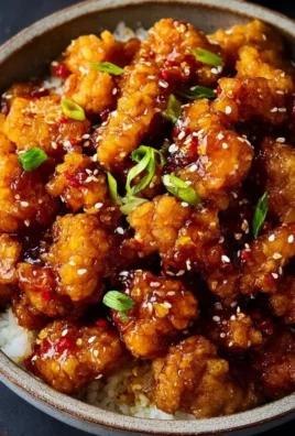 Delicious crispy orange chicken with vibrant sauce and fresh garnish.